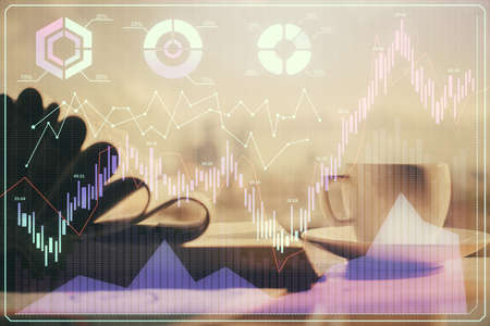 Double exposure of financial chart drawing and desktop with coffee and items on table background. Concept of forex market tradingの写真素材