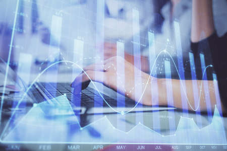 Multi exposure of woman hands typing on computer and financial graph hologram drawing. Stock market...