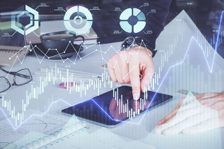 Double exposure of mans hands holding and using a digital device and forex graph drawing. Financial...