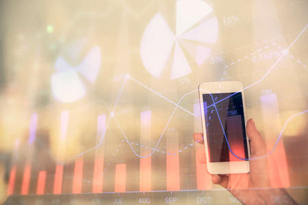 Double exposure of forex chart sketch hologram and woman holding and using a mobile device. Stock market concept.の写真素材