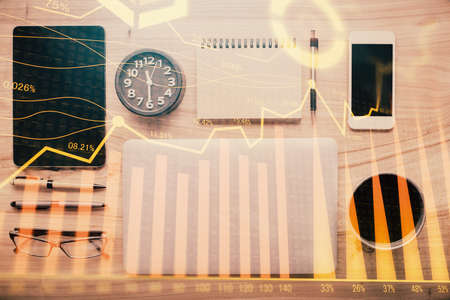 Double exposure of forex graph hologram over desktop with phone. Top view. Mobile trade platform concept.の写真素材
