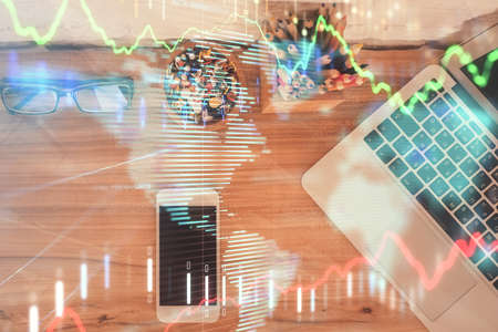 Double exposure of financial graph hologram over desktop with phone. Top view. Mobile trade platform concept.の写真素材