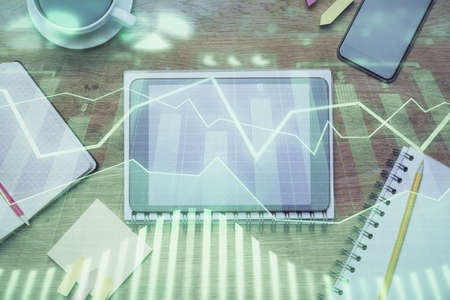 Double exposure of forex chart hologram over desktop with phone. Top view. Mobile trade platform...