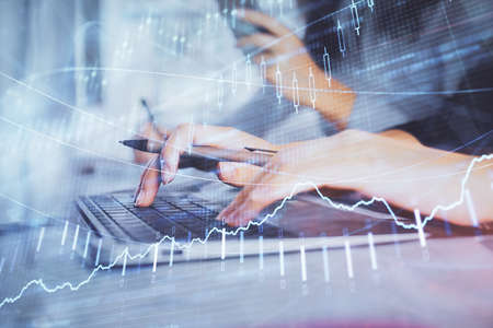 Multi exposure of woman hands typing on computer and financial graph hologram drawing. Stock market...