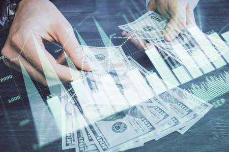 Multi exposure of financial graph drawing hologram and USA dollars bills and man hands. Analysis...