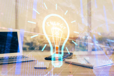 Computer on desktop in office with bulb icon hologram. Double exposure. Concept of idea.の写真素材