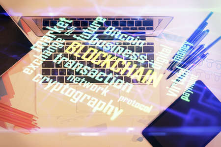 Blockchain theme hologram drawings over computer on the desktop background. Top view. Multi...