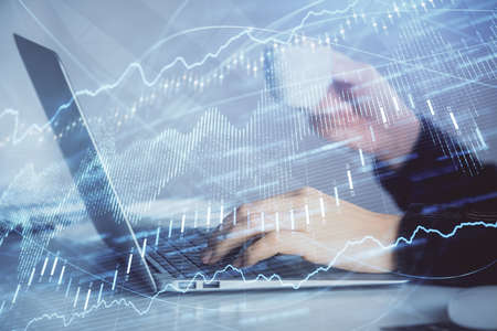 Double exposure of businesswoman hands typing on computer and forex graph hologram drawing....