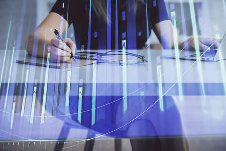 Double exposure of businesswoman hands typing on computer and forex chart hologram drawing....