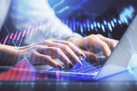 Double exposure of businesswoman hands typing on computer and forex chart hologram drawing....