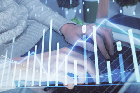 Double exposure of woman hands typing on computer and forex chart hologram drawing. Stock market...