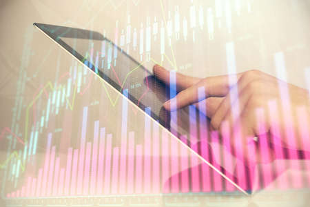 Multi exposure of mans hands holding and using a digital phone and forex graph drawing. Financial...
