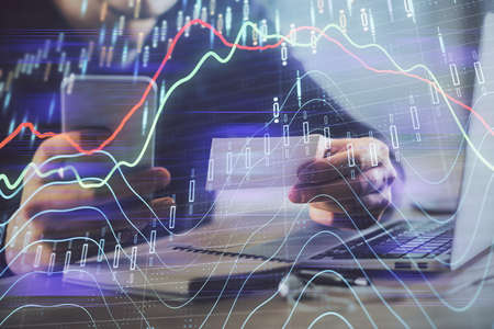 Double exposure of mans hands holding and using a phone and financial graph drawing. Analysis...