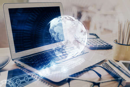 Double exposure of desktop with computer and world map hologram. International data network concept.