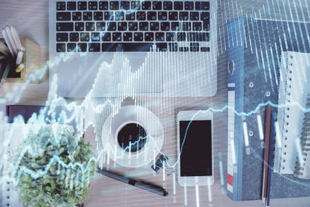 Double exposure of financial graph hologram over desktop with phone. Top view. Mobile trade platform...