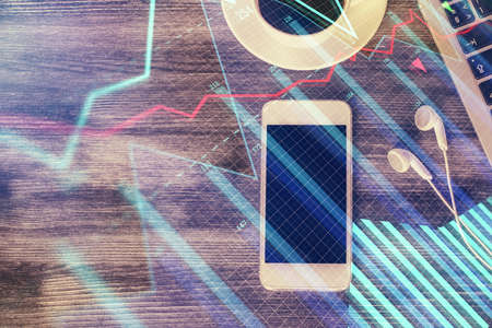 Double exposure of forex chart hologram over desktop with phone. Top view. Mobile trade platform concept.の写真素材