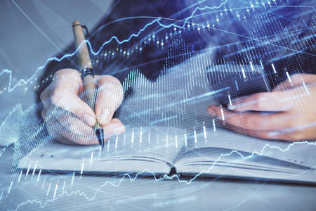 Double exposure of businesswoman hands typing on computer and forex graph hologram drawing....