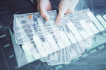 Multi exposure of financial graph drawing hologram and USA dollars bills and man hands. Analysis concept.の写真素材