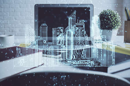 Desktop computer background in office and big town buildings hologram drawing. Double exposure....