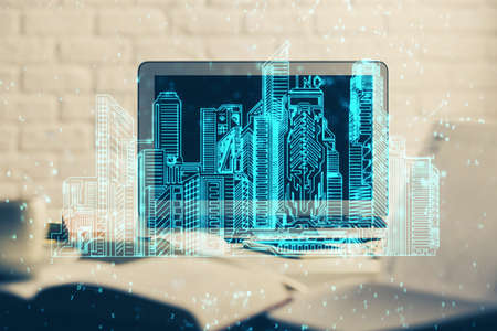 Desktop computer background in office and big town buildings hologram drawing. Double exposure....