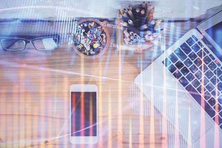 Double exposure of financial graph hologram over desktop with phone. Top view. Mobile trade platform...