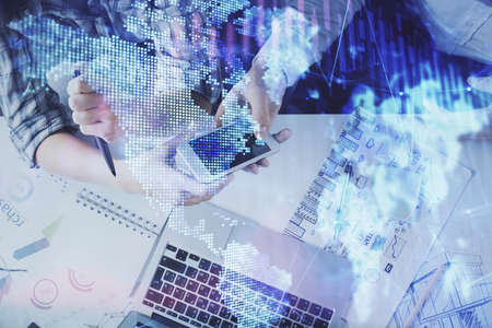 Double exposure of forex graph drawing and man and woman working together holding and using a mobile...