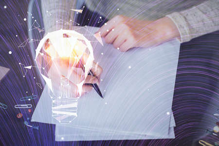 Bulb hologram over hands taking notes background. Concept of idea. Double exposureの写真素材