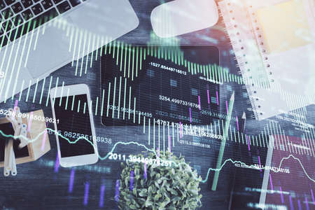 Double exposure of forex chart hologram over desktop with phone. Top view. Mobile trade platform concept.の写真素材