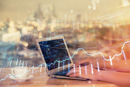 Double exposure of businesswoman hands typing on computer and forex chart hologram drawing....