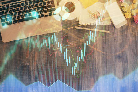 Financial market graph and top view computer on the desktop background. Double exposure. Investment...
