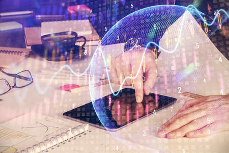 Double exposure of man's hands holding and using a digital device and forex graph drawing. Financial...