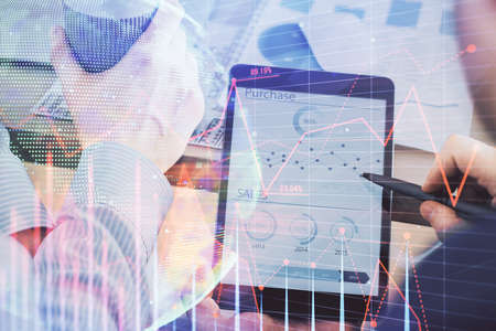 Double exposure of man's hands holding and using a phone and financial chart drawing. Market...
