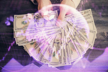 Multi exposure of financial graph drawing hologram and USA dollars bills and man hands. Analysis...