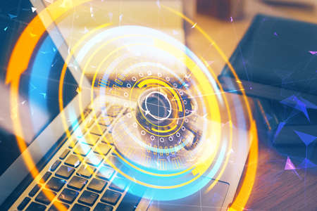 Computer on desktop in office with technology theme hologram. Double exposure. Tech concept.