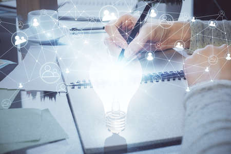 Bulb hologram over hands taking notes background. Concept of idea. Double exposureの写真素材