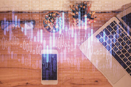 Double exposure of financial graph hologram over desktop with phone. Top view. Mobile trade platform concept.の写真素材