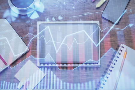 Double exposure of forex chart hologram over desktop with phone. Top view. Mobile trade platform...