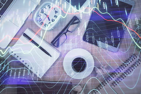 Double exposure of financial chart hologram over desktop with phone. Top view. Mobile trade platform...