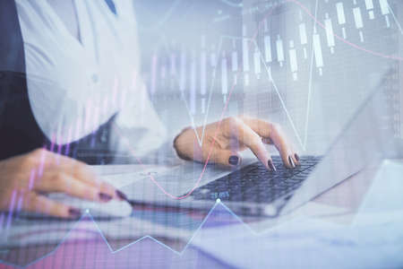 Double exposure of businesswoman hands typing on computer and forex graph hologram drawing....