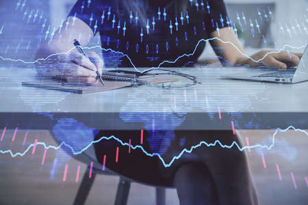 Double exposure of businesswoman hands typing on computer and forex chart hologram drawing....