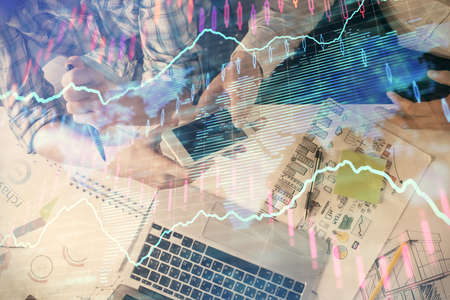 Double exposure of forex graph drawing and man and woman working together holding and using a mobile...