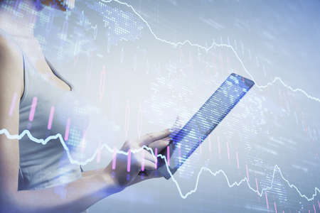 Double exposure of forex chart sketch hologram and woman holding and using a mobile device....