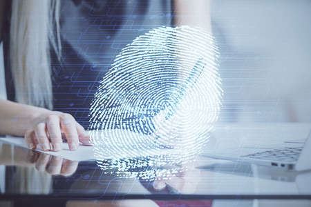 Blue fingerprint hologram over woman's hands taking notes background. Concept of protection. Double exposureの写真素材