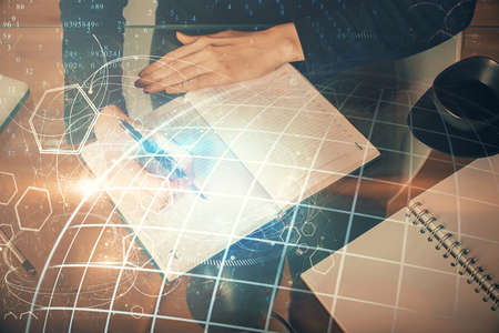Double exposure of hands making notes with world map hologram and data theme icons. Concept of...