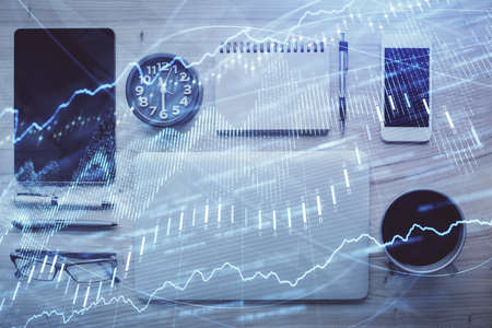 Double exposure of forex graph hologram over desktop with phone. Top view. Mobile trade platform...