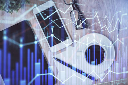Double exposure of forex chart hologram over desktop with phone. Top view. Mobile trade platform concept.の写真素材