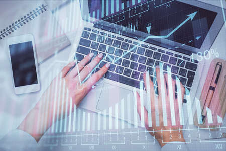 Double exposure of woman hands working on computer and forex graph hologram drawing. Top View....
