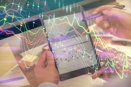 Double exposure of man's hands holding and using a phone and financial chart drawing. Market analysis concept.の写真素材