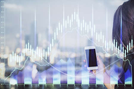 Double exposure of forex chart sketch hologram and woman holding and using a mobile device. Stock...
