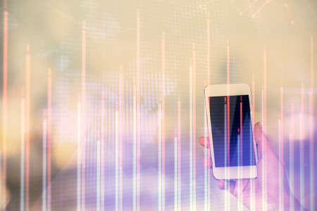 Double exposure of forex chart sketch hologram and woman holding and using a mobile device. Stock...